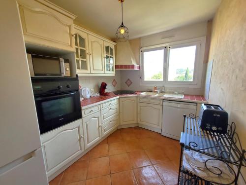 une cuisine avec des armoires blanches, un évier et une fenêtre dans l'établissement Bienvenue à La Seyne-sur-Mer ! 2 chambres, climatisation, Wifi, à La Seyne-sur-Mer