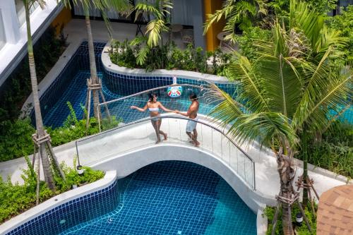 a man and a woman standing on a rail in a swimming pool at Wyndham Garden Naithon Phuket in Nai Thon Beach