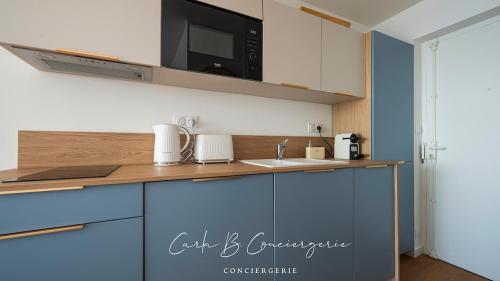 - une cuisine avec des placards bleus et un four micro-ondes dans l'établissement Le RÊVE BLEU CONCARNEAU 2 pers face à la mer, à Concarneau
