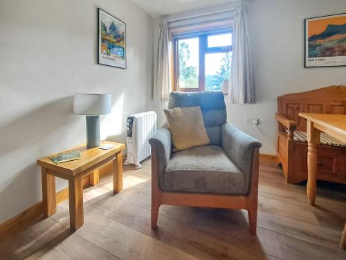 a living room with a chair and a table at Garden Lodge in Llanvair Waterdine