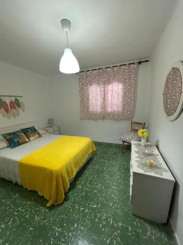 a bedroom with a yellow bed and a table at Casita Rural La Rosa de la Huerta con chimenea interior in Monachil