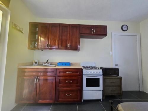 a kitchen with wooden cabinets and a white stove at Tiny Bliss Apartments in Potters Village