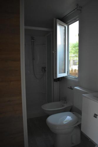 a bathroom with a toilet and a sink and a window at OasiHome in SantʼAndrea