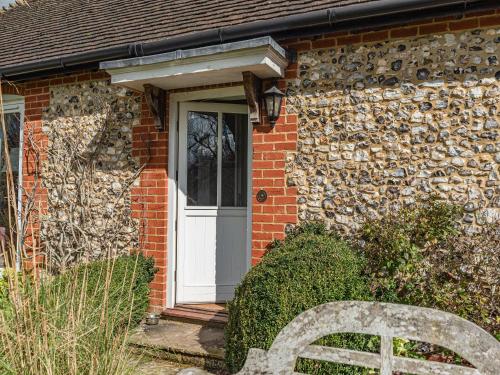 a brick house with a white door and a bench at The Fishing Lodge in Amesbury