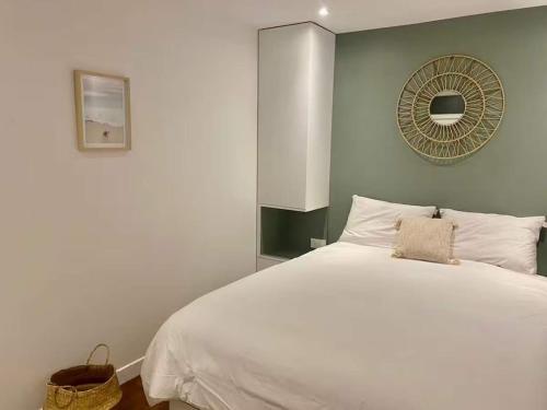 une chambre avec un lit blanc et un miroir dans l'établissement L'écrin de Pierre, Cozy apartment for 4 in Paris, à Paris