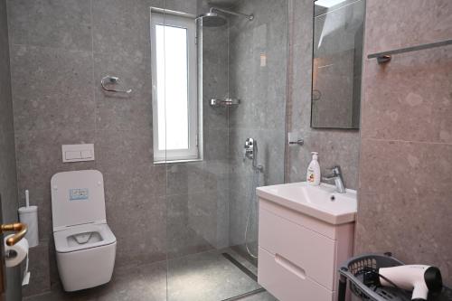 a bathroom with a shower and a toilet and a sink at Amos Apartment in Sarandë