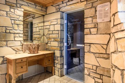 Habitación con paredes de piedra y escritorio de madera frente a una ventana. en Aktiv & Spa Hotel Alpenrose, en Schruns