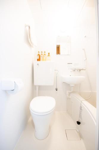 a white bathroom with a toilet and a sink at Osaka U-Shuku in Osaka