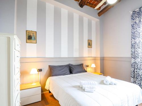 a bedroom with a white bed and striped wall at Tuscan Nest - in Montecatini Alto in Montecatini Alto