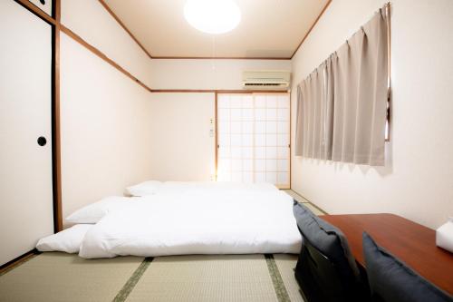 a bedroom with a white bed and a window at Osaka U-Shuku in Osaka