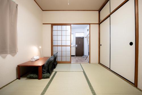 a room with a table and a couch and a door at Osaka U-Shuku in Osaka