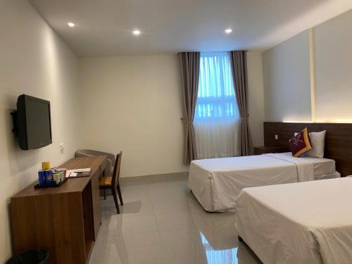 a hotel room with two beds and a television at SÀI GÒN - BẠC LIÊU Hotel in Bạc Liêu