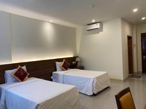 a hotel room with two beds with white sheets at SÀI GÒN - BẠC LIÊU Hotel in Bạc Liêu