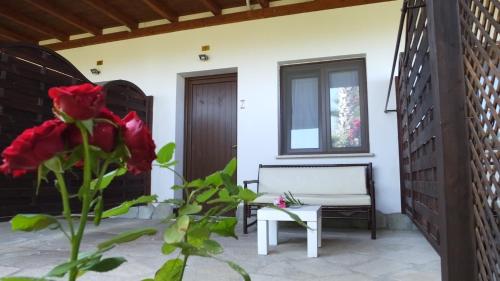 a patio with a bench and a red flower at Hotel Rurale Orti di Nora & SPA in Santa Margherita di Pula