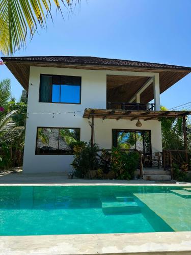 a villa with a swimming pool in front of a house at Sand Beach Boutique Apartments in Bwejuu
