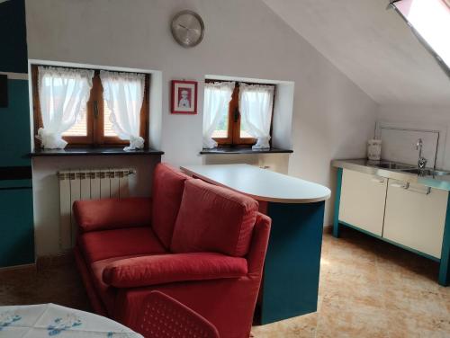 a living room with a red chair and a kitchen at Mansarda Giaveno in Giaveno