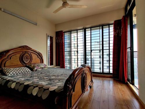 a bedroom with a large bed and large windows at Dar Al Habib in Dhaka