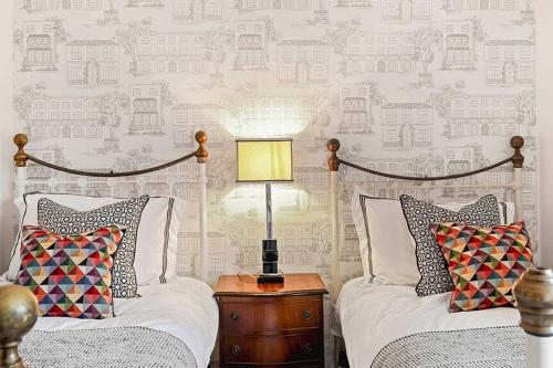 a bedroom with two beds and a lamp on a night stand at Large Stylish House-2 Parking Spaces-Garden-Fire in Winchcombe