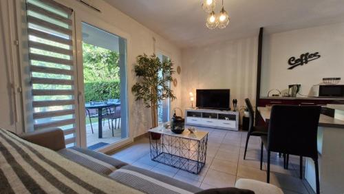 un salon avec un canapé, une table et une télévision dans l'établissement Royan - APPARTEMENT en rez-de-chaussée aménagé avec ELEGANCE - jardin privatif, à Royan