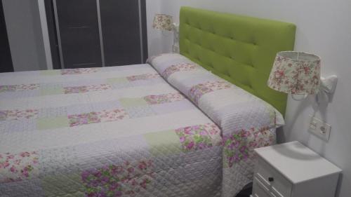 a bedroom with a bed with a green headboard at Hostal Boutique Bajamar in Nerja