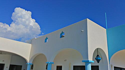 a white building with a blue sky and a cloud at Villa Star of the Sea in Barra de Navidad