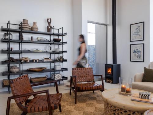 a woman walking through a living room with a fireplace at Goats Window Luxury Safari Lodge in Bonnievale