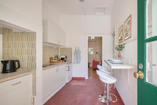 a kitchen with white cabinets and a green door at Pateo do Tempo in Carcavelos