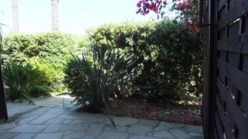 a garden with bushes and a stone walkway at Hotel Rurale Orti di Nora & SPA in Santa Margherita di Pula