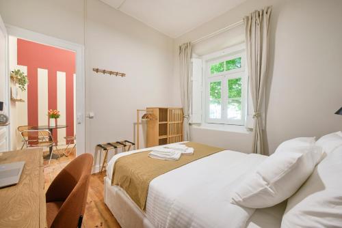 a bedroom with a bed and a desk and a window at Pateo do Tempo in Carcavelos