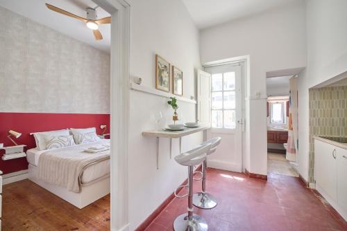 a bedroom with a bed and a stool in a room at Pateo do Tempo in Carcavelos