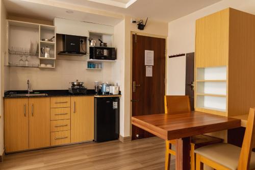a small kitchen with a wooden table and a black refrigerator at POKHARA APARTMENTS INN in Pokhara