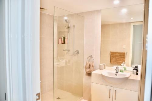 a bathroom with a glass shower and a sink at Alex Beach Apartment in Alexandra Headland