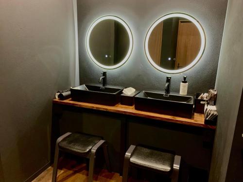 a bathroom with two sinks and two mirrors at Black Penthouse Naha 最大12名宿泊可 118平米 国際通り沿い 牧志駅 徒歩5分 in Naha