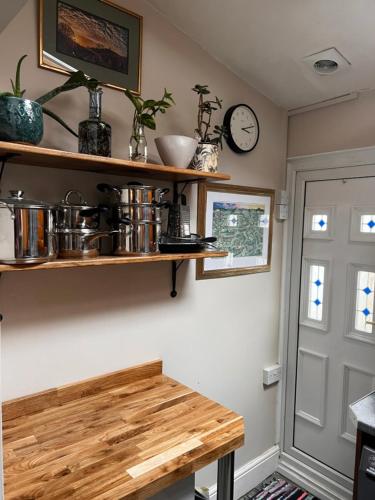 a kitchen with wooden shelves and a clock on the wall at Little Hive in the Heartlands in Glastonbury