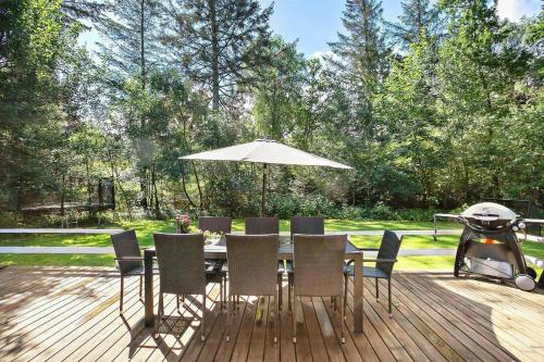 a table with chairs and an umbrella on a deck at Log Cabin Near Mariager Fjord in Hadsund