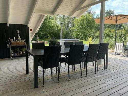 a black dining table and chairs on a deck at Summerhouse With Hot Tub On Langeland in Tranekær