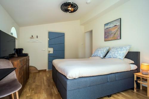 a bedroom with a blue bed and a television at Gastsuite het Duinroosje met hottub op het privé terras! in Den Burg