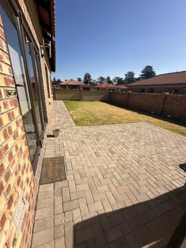a brick patio outside of a building with a yard at Lloyds - unit 10 in Ermelo