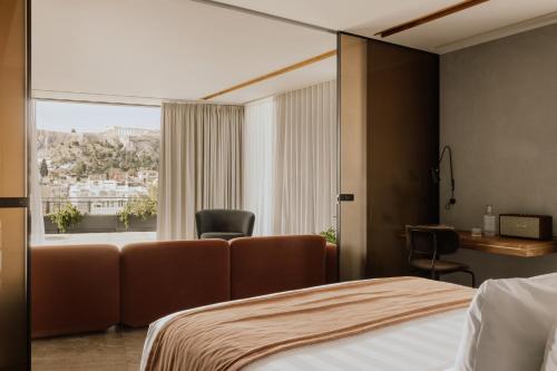 a bedroom with a bed and a chair and a window at Perianth Hotel, a Member of Design Hotels in Athens