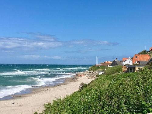 a sandy beach with houses and the ocean at Historic Farm Atmosphere In Tisvildeleje in Tisvilde