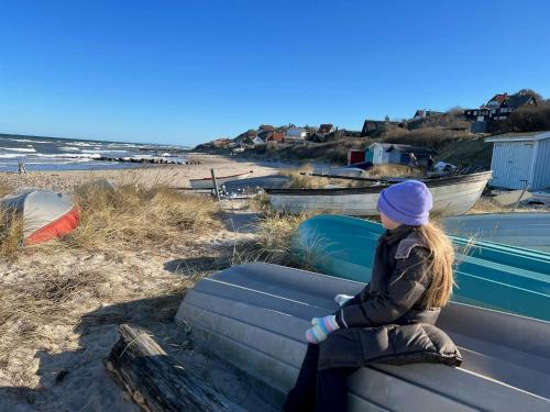 a young girl sitting on a bench at the beach at Historic Farm Atmosphere In Tisvildeleje in Tisvilde