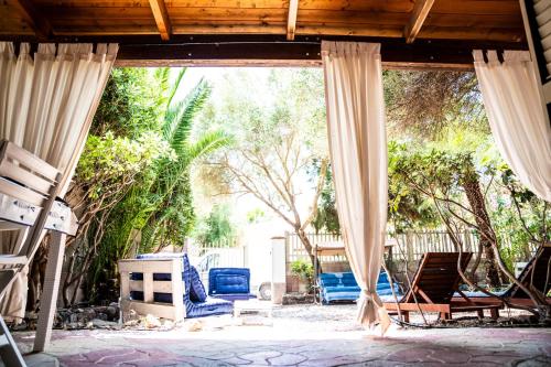 an outdoor patio with blue chairs and curtains at Casa Josto a due passi da Spiaggia Maladroxia in Maladroxia