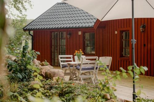 a red cabin with a table and chairs and an umbrella at Quaint Barn Nestled Between Sea And Forest in Båstad
