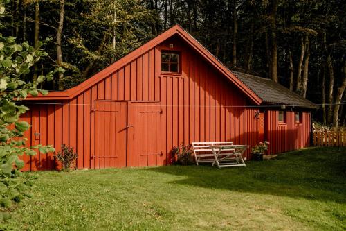 a red barn with a bench in front of it at Quaint Barn Nestled Between Sea And Forest in Båstad