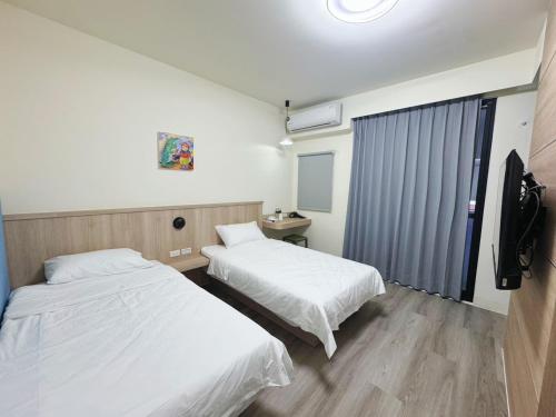 a hotel room with two beds and a television at 海洋星空民宿 in Magong