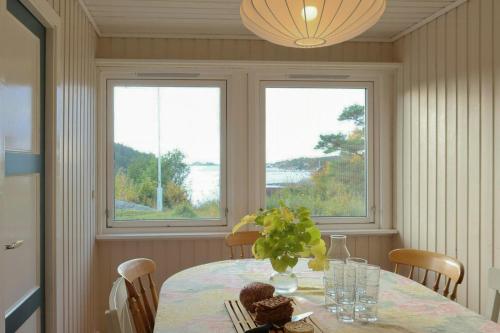a dining room with a table and two windows at Summer Cabin With Sea View In Southern Norway in Jordtveit