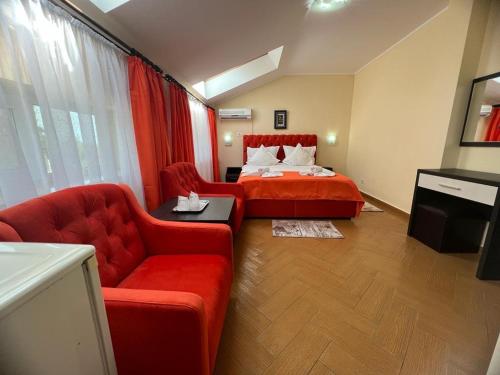 a bedroom with a red bed and a red couch at Hotel Vera in Eforie Nord