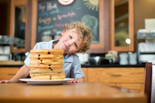 a little boy sitting at a table with a plate of food at AmericInn by Wyndham Pampa Event Center in Pampa