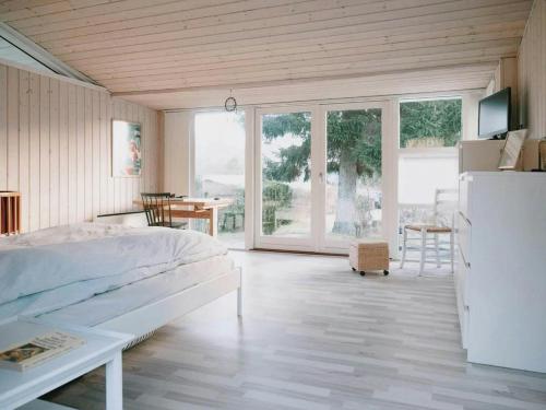 a bedroom with a bed and a table and windows at Moments In Relaxed Family House Near Kulhuse in Jægerspris