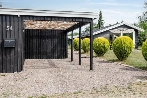 a black garage with a building with bushes at Beautiful Tranquil Home By Fjord Near Copenhagen in Holbæk